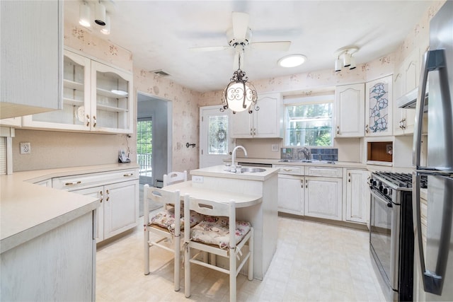 810 Tooker Ave, West Babylon, NY 11704 - kitchen featuring stainless steel appliances, wallpapered walls, light countertops, a center island with sink, and a ceiling fan