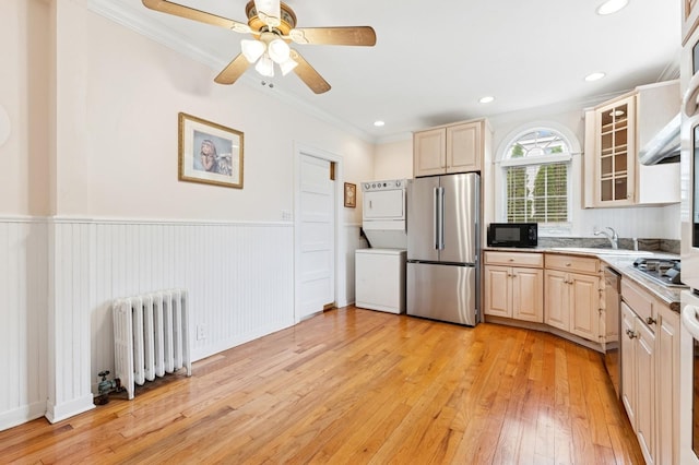 57 Maple Ave, Bay Shore, NY 11706 - kitchen featuring appliances with stainless steel finishes, stacked washer and clothes dryer, radiator, light wood-style flooring, and ornamental molding