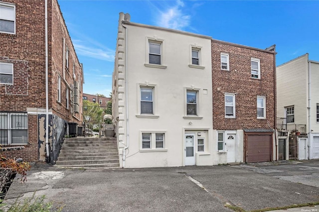53-42 63rd St, Maspeth, NY 11378 - view of front of property with a garage, driveway, and stucco siding
