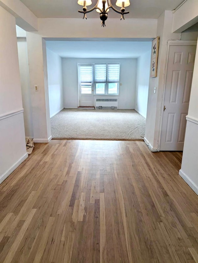 325 King St Unit 6J, Port Chester, NY 10573 - unfurnished dining area featuring radiator, a chandelier, and wood finished floors