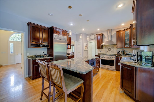 2 Marion Way, Lagrangeville, NY 12540 - kitchen featuring wall chimney range hood, built in appliances, a center island, light wood-type flooring, and backsplash