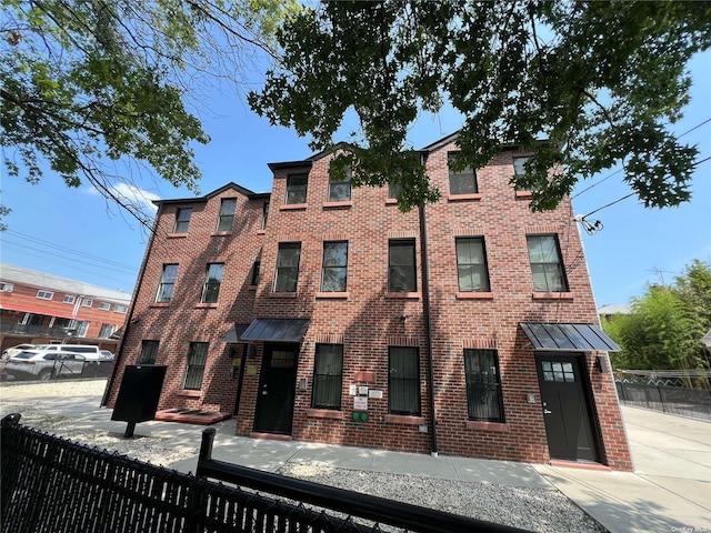 56-75 136th St Unit 3B, Flushing, NY 11354 - view of front facade featuring a fenced front yard, brick siding, and a standing seam roof