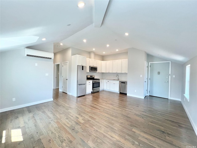 56-75 136th St Unit 3B, Flushing, NY 11354 - kitchen featuring stainless steel appliances, a wall unit AC, lofted ceiling, a sink, and open floor plan