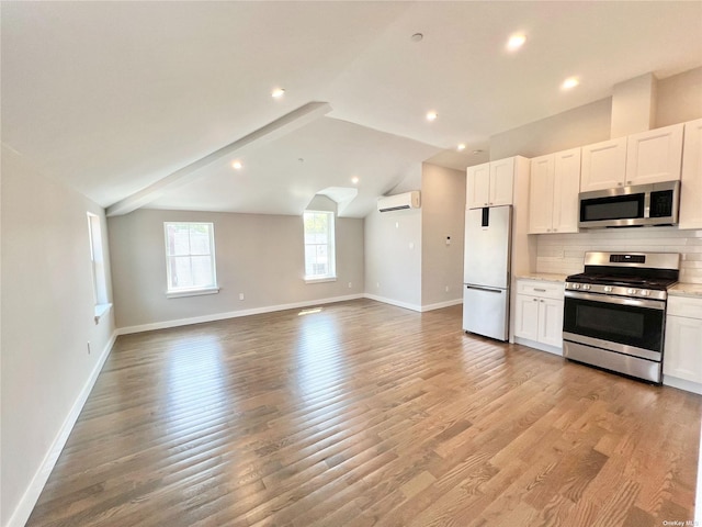 56-75 136th St Unit 3B, Flushing, NY 11354 - kitchen featuring appliances with stainless steel finishes, a wall mounted AC, baseboards, open floor plan, and decorative backsplash