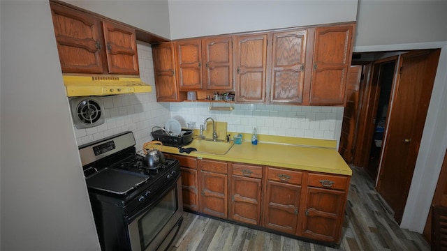 5214 92nd St, Elmhurst, NY 11373 - kitchen with stainless steel range with gas stovetop, under cabinet range hood, decorative backsplash, a sink, and light countertops