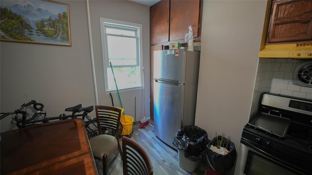5214 92nd St, Elmhurst, NY 11373 - kitchen with stainless steel stove, freestanding refrigerator, under cabinet range hood, wood finished floors, and backsplash