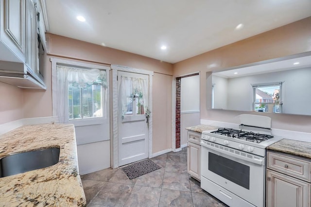56 Mary St, Valley Stream, NY 11580 - kitchen with white gas range, light stone counters, recessed lighting, baseboards, and a sink