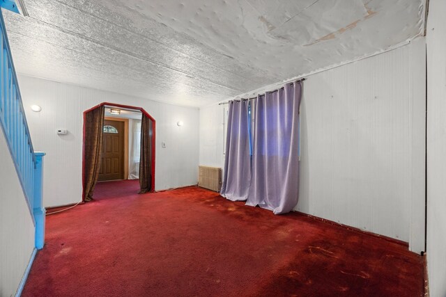 12104 Linden Blvd, South Ozone Park, NY 11420 - empty room with carpet floors, arched walkways, radiator, and wooden walls