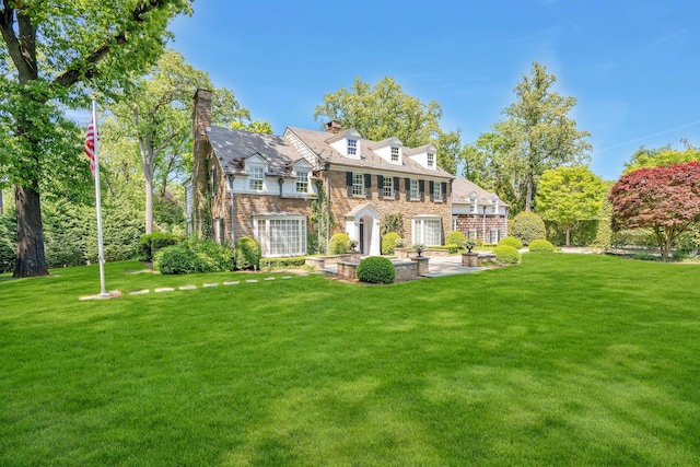 191 Elderfields Rd, Manhasset, NY 11030 - rear view of house with a yard, a patio, a chimney, and stone siding