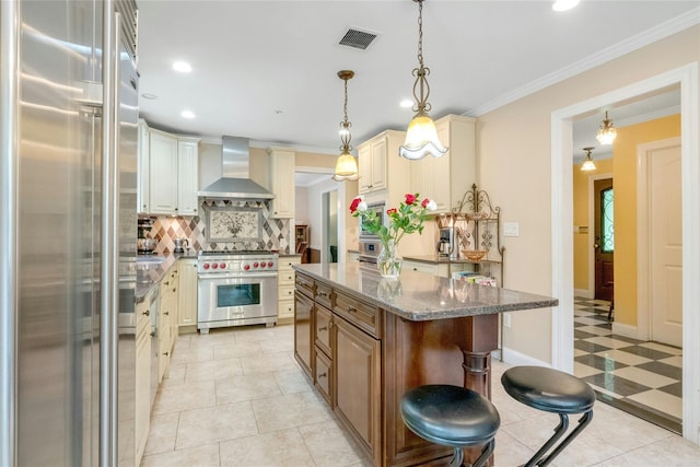 100 Castle Rd, Chappaqua, NY 10514 - kitchen with premium appliances, wall chimney exhaust hood, decorative backsplash, cream cabinetry, and light stone counters