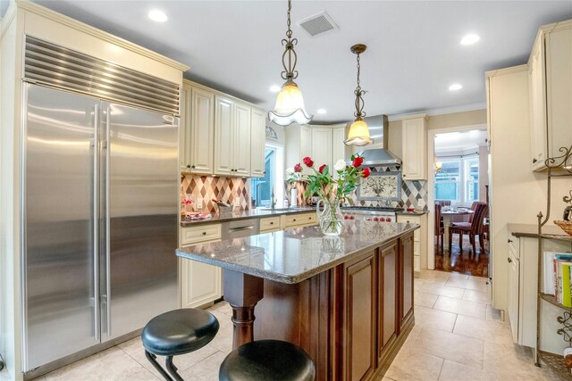 100 Castle Rd, Chappaqua, NY 10514 - kitchen featuring built in refrigerator, wall chimney exhaust hood, cream cabinetry, tasteful backsplash, and recessed lighting