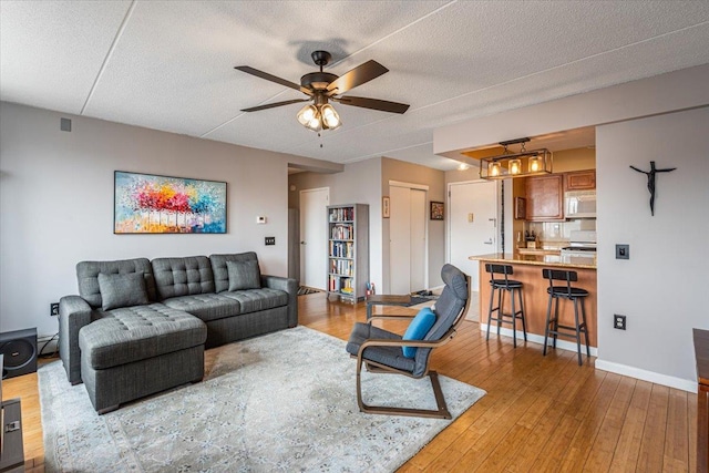 342 E 119th St Unit 6D, New York Manhattan, NY 10035 - living area with light wood-style flooring, a ceiling fan, baseboards, and a textured ceiling
