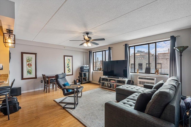 342 E 119th St Unit 6D, New York Manhattan, NY 10035 - living area with a textured ceiling, a ceiling fan, a wall mounted AC, light wood finished floors, and baseboards