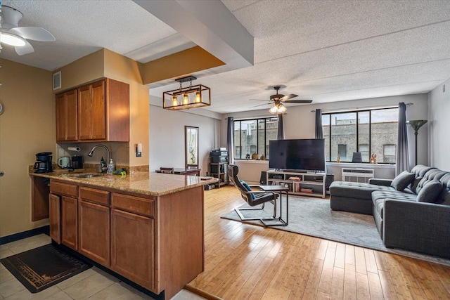 342 E 119th St Unit 6D, New York Manhattan, NY 10035 - kitchen with a sink, a ceiling fan, a textured ceiling, brown cabinetry, and open floor plan