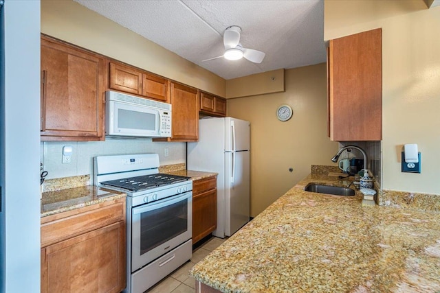 342 E 119th St Unit 6D, New York Manhattan, NY 10035 - kitchen with white appliances, a sink, ceiling fan, brown cabinets, and light stone counters