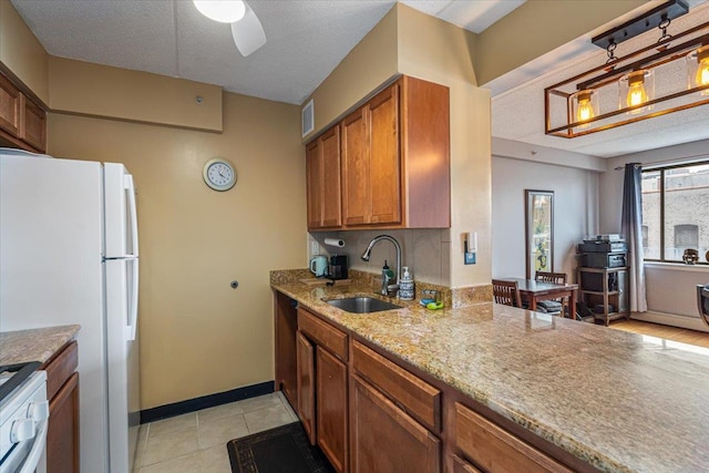 342 E 119th St Unit 6D, New York Manhattan, NY 10035 - kitchen with a sink, brown cabinets, a ceiling fan, light stone counters, and stainless steel range with gas stovetop