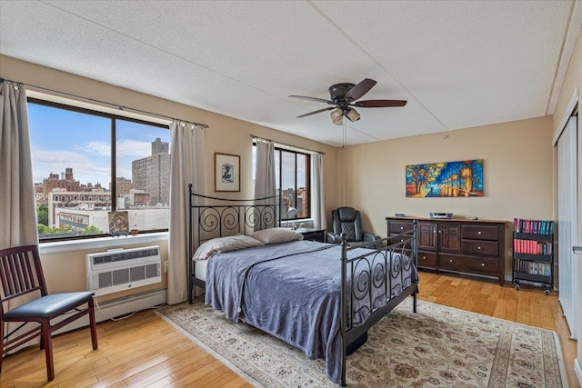 342 E 119th St Unit 6D, New York Manhattan, NY 10035 - bedroom with hardwood / wood-style floors, a textured ceiling, a city view, a wall mounted air conditioner, and a ceiling fan