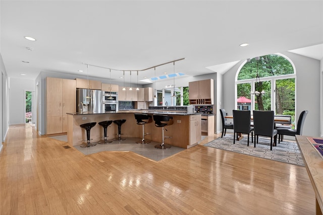 109 Sleight Plass Rd, Poughkeepsie, NY 12603 - kitchen featuring appliances with stainless steel finishes, light wood finished floors, dark countertops, a kitchen bar, and recessed lighting