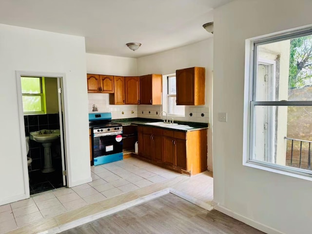 1372 E 94th St, Brooklyn, NY 11236 - kitchen featuring stainless steel range with electric stovetop, a sink, decorative backsplash, brown cabinets, and baseboards