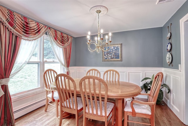 285 Willow Grove Rd, Stony Point, NY 10980 - dining space with a baseboard heating unit, a chandelier, a decorative wall, wainscoting, and wood finished floors