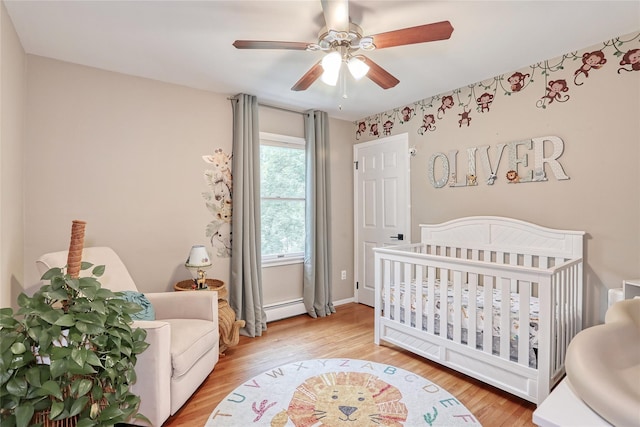 285 Willow Grove Rd, Stony Point, NY 10980 - bedroom with light wood-type flooring, a nursery area, baseboard heating, and a ceiling fan
