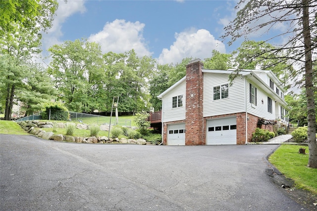 285 Willow Grove Rd, Stony Point, NY 10980 - view of home's exterior with asphalt driveway, brick siding, a chimney, and an attached garage