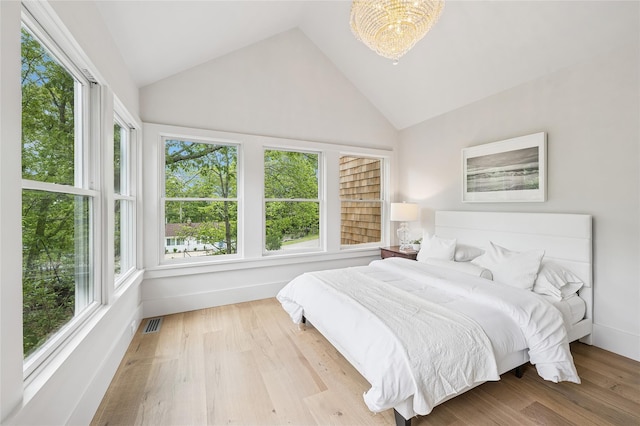 69 Bay View Dr W, Sag Harbor, NY 11963 - bedroom with multiple windows, wood finished floors, a chandelier, and high vaulted ceiling