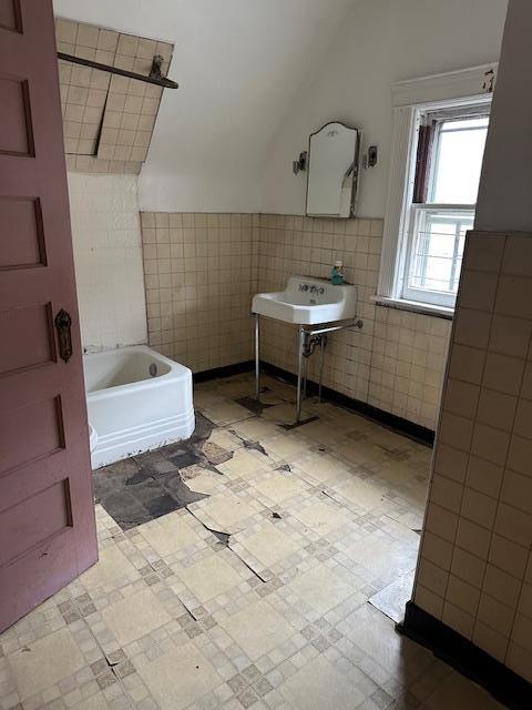 689 E 19th St, Brooklyn, NY 11230 - full bath with tile walls, a tub, vaulted ceiling, tile patterned floors, and a sink