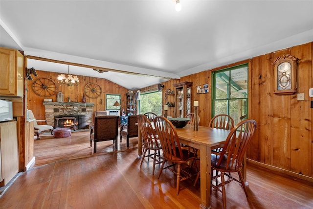 11 Waldweg Dr, Sparrowbush, NY 12780 - dining area with wood walls, wood-type flooring, vaulted ceiling, a fireplace, and a chandelier