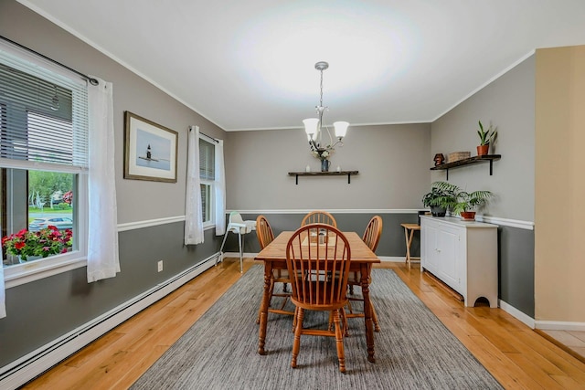 370 Pheasant Pl, Greenport, NY 11944 - dining space with a baseboard heating unit, a chandelier, ornamental molding, light wood-type flooring, and baseboards