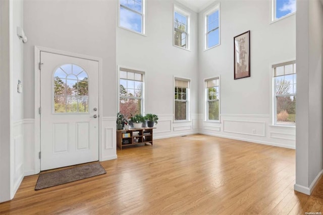 55 Hamptons Court Dr E Unit 55, Eastport, NY 11941 - entryway featuring wood finished floors, a wainscoted wall, a towering ceiling, and a decorative wall