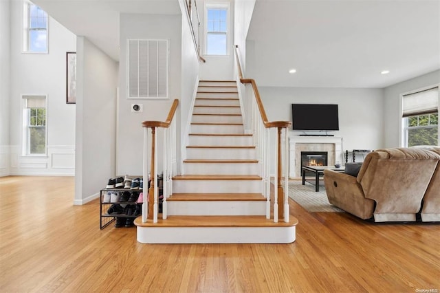 55 Hamptons Court Dr E Unit 55, Eastport, NY 11941 - stairway featuring wood finished floors, a glass covered fireplace, recessed lighting, and a wainscoted wall