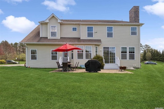 55 Hamptons Court Dr E Unit 55, Eastport, NY 11941 - rear view of property featuring a chimney, entry steps, a lawn, and a patio area