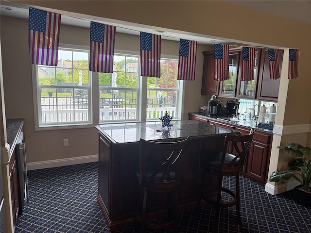 55 Hamptons Court Dr E Unit 55, Eastport, NY 11941 - kitchen featuring dark carpet, baseboards, a kitchen island, and dark stone counters