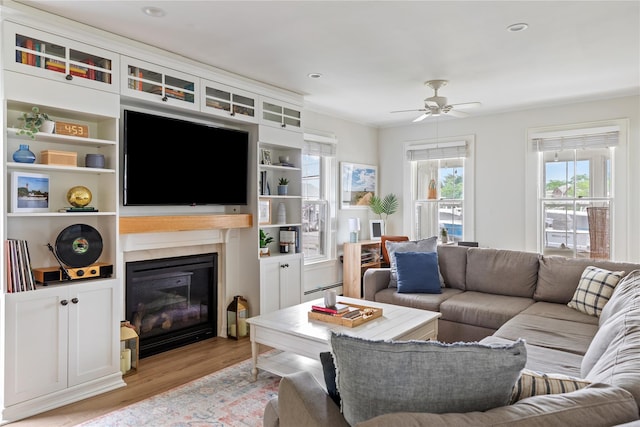 28 Shore Rd, Babylon, NY 11702 - living area with light wood-type flooring, a ceiling fan, a glass covered fireplace, and a baseboard heating unit