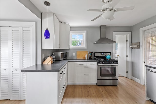 28 Shore Rd, Babylon, NY 11702 - kitchen with wall chimney exhaust hood, appliances with stainless steel finishes, dark countertops, white cabinetry, and light wood-style floors