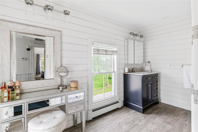 28 Shore Rd, Babylon, NY 11702 - bathroom featuring baseboard heating, wooden walls, wood finished floors, vanity, and plenty of natural light