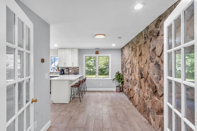 167 Grandview Ave, Nanuet, NY 10954 - kitchen with french doors, a kitchen breakfast bar, white cabinets, light wood-type flooring, and light countertops