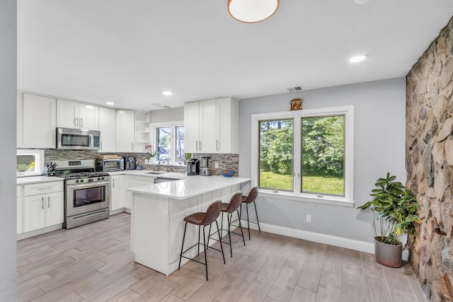 167 Grandview Ave, Nanuet, NY 10954 - kitchen featuring stainless steel appliances, open shelves, a breakfast bar, decorative backsplash, and recessed lighting