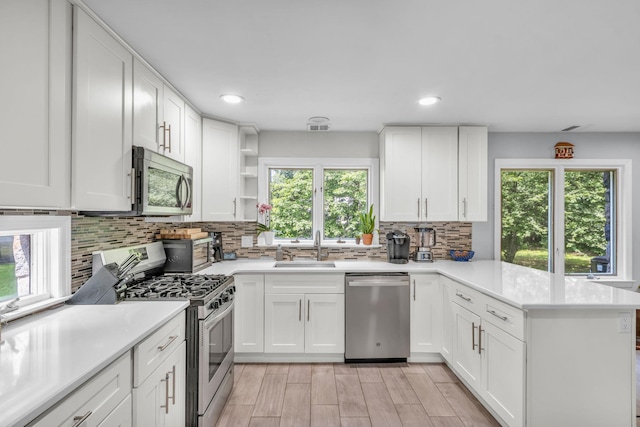 167 Grandview Ave, Nanuet, NY 10954 - kitchen with stainless steel appliances, a peninsula, decorative backsplash, light countertops, and white cabinets