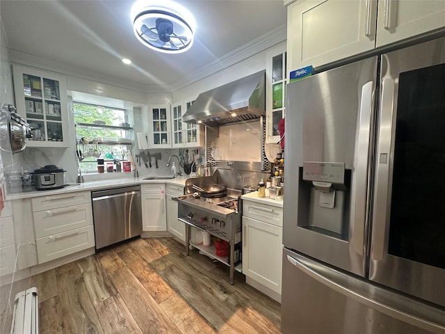 313 88th St, Brooklyn, NY 11209 - kitchen featuring stainless steel appliances, wall chimney exhaust hood, ornamental molding, light countertops, and wood finished floors