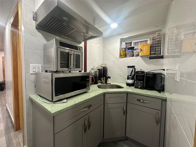 313 88th St, Brooklyn, NY 11209 - kitchen featuring stainless steel microwave, a sink, wall chimney exhaust hood, gray cabinetry, and light stone counters