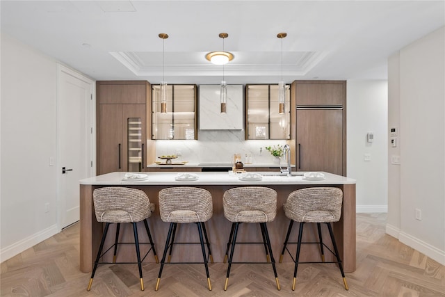 78-29 Austin St Unit Th1, Forest Hills, NY 11375 - kitchen featuring a tray ceiling, baseboards, a large island with sink, light countertops, and a breakfast bar