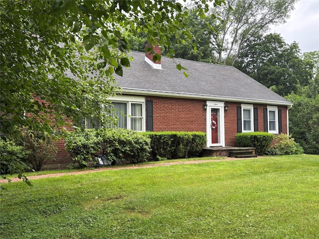 15 Orchard Rd, Poughkeepsie, NY 12603 - view of front facade with a chimney, brick siding, a front yard, and roof with shingles