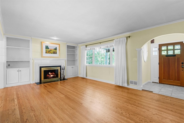 4 Senate Pl, Larchmont, NY 10538 - unfurnished living room featuring arched walkways, a fireplace with flush hearth, crown molding, built in features, and light wood-type flooring