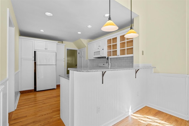 4 Senate Pl, Larchmont, NY 10538 - kitchen featuring white appliances, a breakfast bar area, wainscoting, white cabinetry, and light wood-style flooring