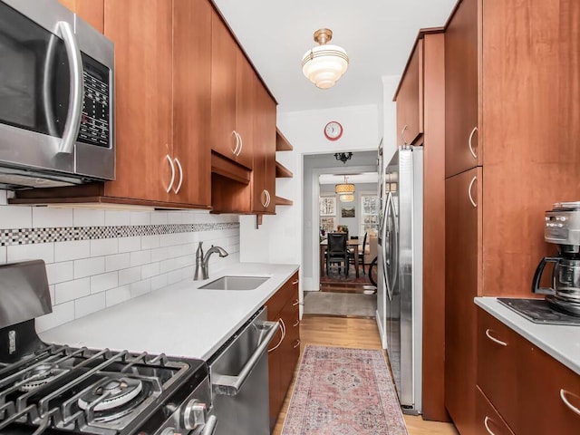 525 W 238th St Unit 1L, Bronx, NY 10463 - kitchen featuring stainless steel appliances, a sink, brown cabinetry, light countertops, and backsplash