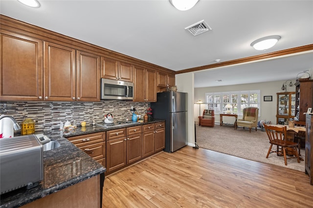 28 Trent Ct Unit B, Ridge, NY 11961 - kitchen with appliances with stainless steel finishes, brown cabinetry, tasteful backsplash, open floor plan, and light wood-type flooring