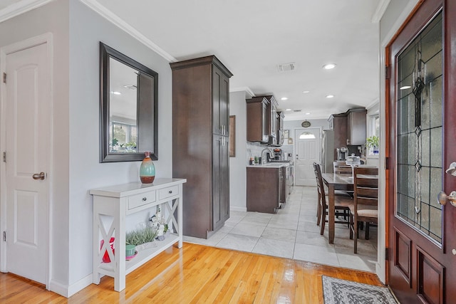 263 Claywood Dr, Brentwood, NY 11717 - kitchen featuring dark brown cabinets, light wood-type flooring, crown molding, light countertops, and baseboards