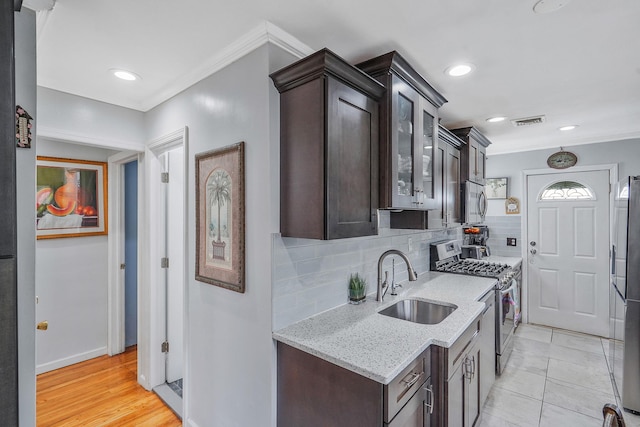 263 Claywood Dr, Brentwood, NY 11717 - kitchen with stainless steel appliances, a sink, dark brown cabinetry, crown molding, and backsplash
